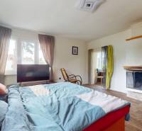 Schlafzimmer in einem Einfamilienhaus mit Kamin, Bett und großem Fenster.