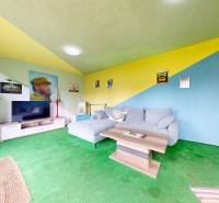 Ein buntes Wohnzimmer in einem Einfamilienhaus mit einem Sofa, einem Couchtisch und einem Fernseher.