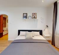 Schlafzimmer in einer Einzimmerwohnung mit Bett, Nachttisch und offenem Zugang zum Flur.
