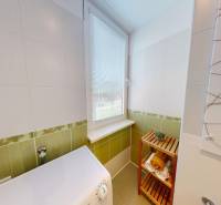 Badezimmer mit Waschmaschine und Regal in einer Einzimmerwohnung, mit dekorativen Fliesen.