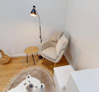 Sessel mit Kissen, kleiner Tisch, Lampe und Dekoration in einer Einzimmerwohnung.