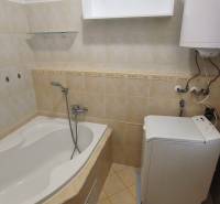 Badezimmer in einer 2-Zimmer-Wohnung mit Badewanne, Boiler und Waschmaschine.