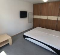 Schlafzimmer mit Doppelbett, Fernseher und Einbauschrank in einer 2-Zimmer-Wohnung.