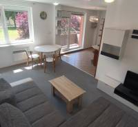 Wohnzimmer in einer Zweizimmerwohnung mit Sofa, Fernseher und Esstisch.