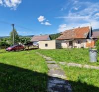 Ein Einfamilienhaus in Mníšek nad Hnilcom mit Rasen, Terrasse und Parkplatz unter klarem Himmel.