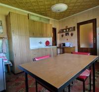 Küche in einem Einfamilienhaus mit Holztisch, Schränken und Geräten.