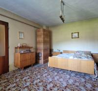 Ein Schlafzimmer in einem Einfamilienhaus mit antiken Möbeln und einem Kachelofen.