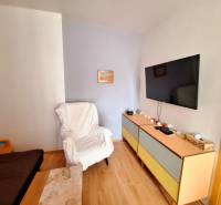 Wohnzimmer in einer 3-Zimmer-Wohnung, mit einem Fernseher an der Wand und bequemen Sesseln.