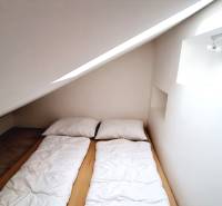 Dachbodenschlafzimmer mit einem Einzelbett und Dachfenster in einer 3-Zimmer-Wohnung.