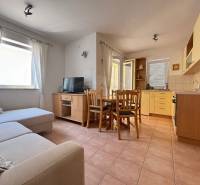 Küche und Wohnzimmer mit Sofa, Esstisch, Fernseher in einer 2-Zimmer-Wohnung.