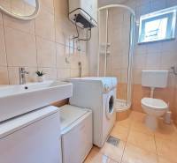 Badezimmer in einer 2-Zimmer-Wohnung mit Waschmaschine, Duschkabine und Toilette.