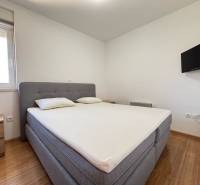 Schlafzimmer mit Doppelbett, Fernseher und Nachttischen in einer Zweizimmerwohnung.