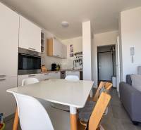 Küche in einer 2-Zimmer-Wohnung mit weißen Geräten und einem Holzesstisch.