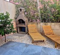 Gartenbereich einer 2-Zimmer-Wohnung in Novalja mit Liegestühlen und Grill, umgeben von Grün.
