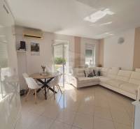Wohnzimmer in einer Zweizimmerwohnung mit weißem Sofa und Esstisch.