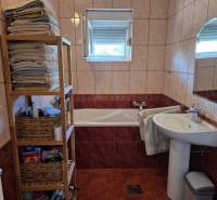 Badezimmer in einer 2-Zimmer-Wohnung mit Badewanne, Regalen und Fenster.