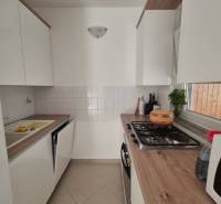 Küche in einer 2-Zimmer-Wohnung, helle Schränke, Herd, Mikrowelle, Holzarbeitsplatte.