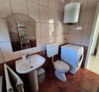 Badezimmer mit Spiegel, Waschbecken, Waschmaschine und Toilette in einer 2-Zimmer-Wohnung.