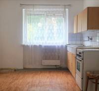 Einfache Küche mit Gasherd, Esstisch und Stuhl in einer 2-Zimmer-Wohnung.
