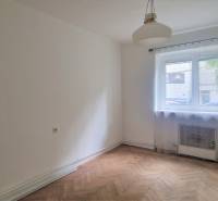 Ein Zimmer mit Holzboden, Fenster und weißen Wänden in einer 2-Zimmer-Wohnung.