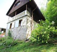 Ein Steinhaus in Holčíkovce, umgeben von Blumen und Grün auf einem hügeligen Gelände.