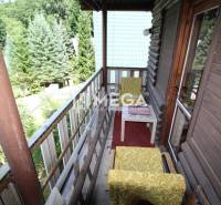 Der Balkon der Hütte in Holčíkovce mit einem hölzernen Geländer und antiken Möbeln, umgeben von Natur.