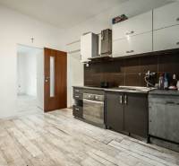 Küche in einer 3-Zimmer-Wohnung mit Holzboden und dunklen Schränken.
