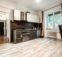 Küche in einer 3-Zimmer-Wohnung mit weißen Möbeln und dunklen Fliesen, heller Raum.