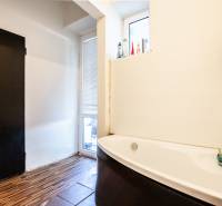 Badezimmer mit Badewanne in einer 3-Zimmer-Wohnung. Weiße Wände, Türen und Holzboden.
