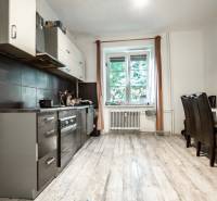 Die Küche in der 3-Zimmer-Wohnung mit dunklen Möbeln und einem Esstisch am Fenster.