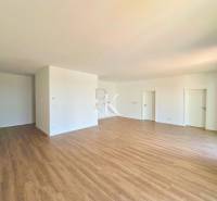 Geräumiges Zimmer mit Holzboden und weißen Wänden in einer 3-Zimmer-Wohnung.