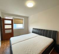 Schlafzimmer mit Doppelbett, Tür und großem Fenster in einer 2-Zimmer-Wohnung.