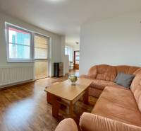 Wohnzimmer in einer Zweizimmerwohnung mit einem orangefarbenen Sofa und einem Holztisch.