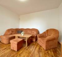 Wohnzimmer mit einer orangefarbenen Couch in einer Zweizimmerwohnung mit Holzboden.