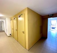 Ein Flur mit mehreren Türen in einer 2-Zimmer-Wohnung, helle Fliesen und ein Notausgang.