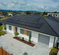 Ein Einfamilienhaus in Piešťany mit Photovoltaikmodulen auf dem Dach ist von einem grünen Garten umgeben.