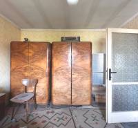 Retro-Möbel mit Holzschränken in einer 3-Zimmer-Wohnung mit Teppichboden und Tapeten.