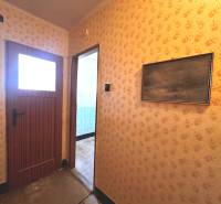 Der Flur in der 3-Zimmer-Wohnung mit gemusterten Tapeten und Holztüren.