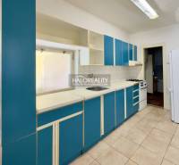 Küche in einem Einfamilienhaus mit blauen Schränken und weißen Geräten.