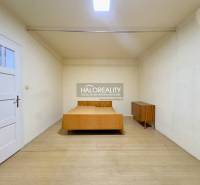Schlafzimmer in einem Einfamilienhaus mit einem Holzbett und einer Kommode, helle Wände und Boden.