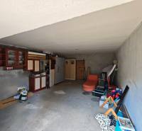 Innenraum einer Garage in einem Einfamilienhaus mit Regalen, Schränken und verschiedenen gelagerten Ausrüstungen.