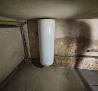 Wassertank im Einfamilienhaus mit abgenutzter Wand und Leitungen.