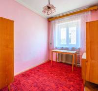 Ein Zimmer in einem Einfamilienhaus mit rosa Wänden, Möbeln und einem roten Teppich.