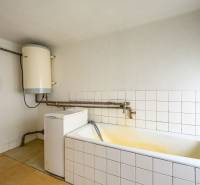 Badezimmer im Einfamilienhaus mit Badewanne, Boiler und Waschmaschine.