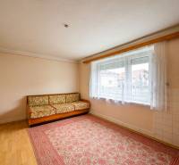 Ein Zimmer in einem Einfamilienhaus mit Teppich, Sofa und großem Fenster.