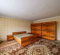 Schlafzimmer im Einfamilienhaus mit Holzmöbeln und Retro-Mustern an den Wänden.