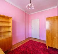 Ein Zimmer in einem Einfamilienhaus mit Holzmöbeln, rotem Teppich und rosa Wänden.