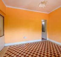 Ein Zimmer in einem Einfamilienhaus mit orangefarbenen Wänden und einem Fliesenmuster auf dem Boden.