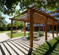 Ein hölzerner Pavillon mit Bänken im Park in Košice, Stadtteil Juh, umgeben von Grün.