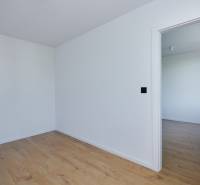 Ein leerer Raum mit Holzboden und offenen Türen in einer Zweizimmerwohnung.